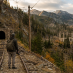 A vintage electric train pulling a freight load through a rugged mountain pass along the Milwaukee Road in Montana.