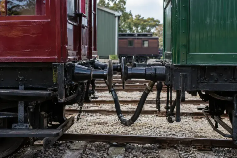 A stationary heritage railway wagon with its connected air-brake hose visible between vehicles in a museum yard.